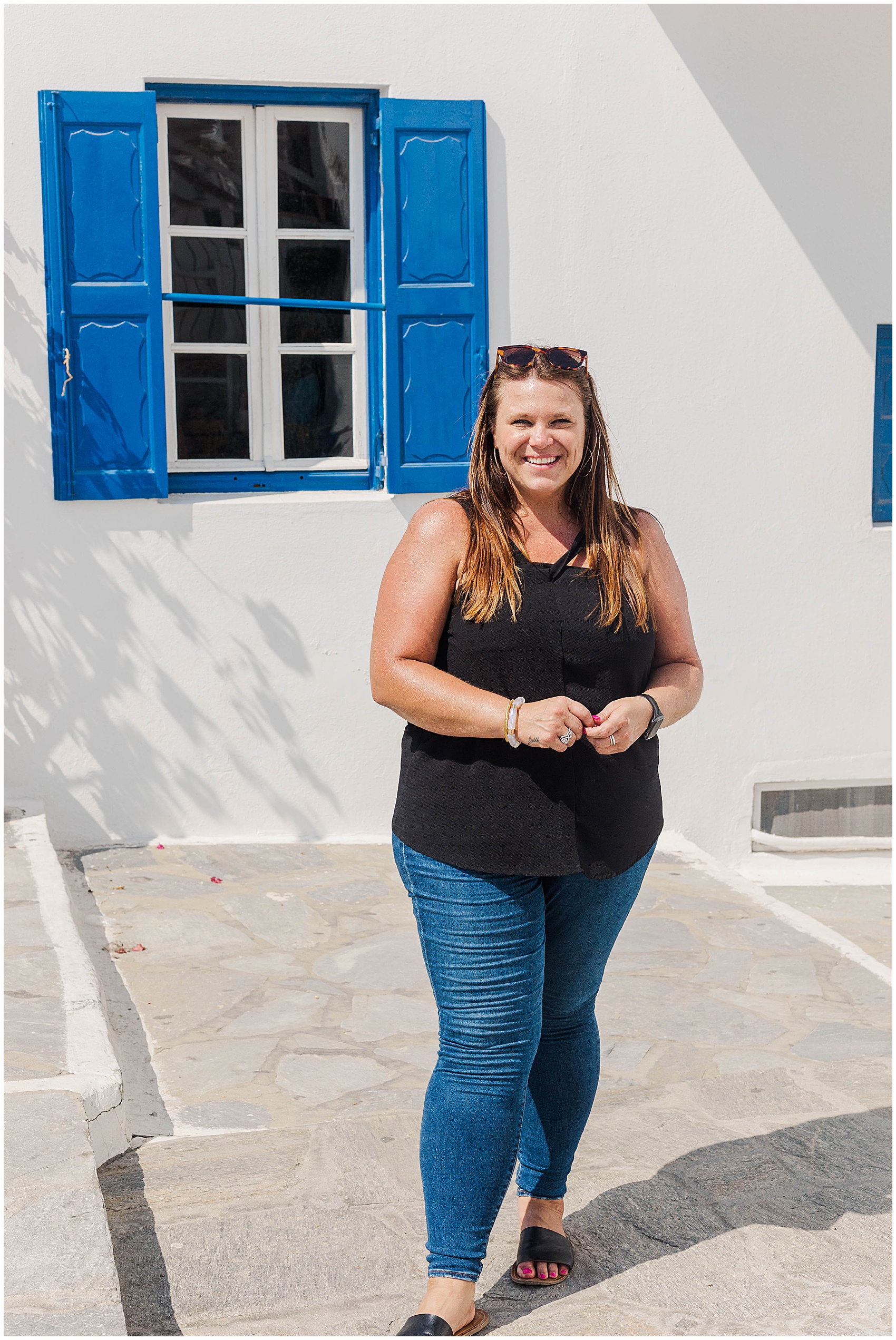 nicole standing in front of blue shutters greece photoshoot