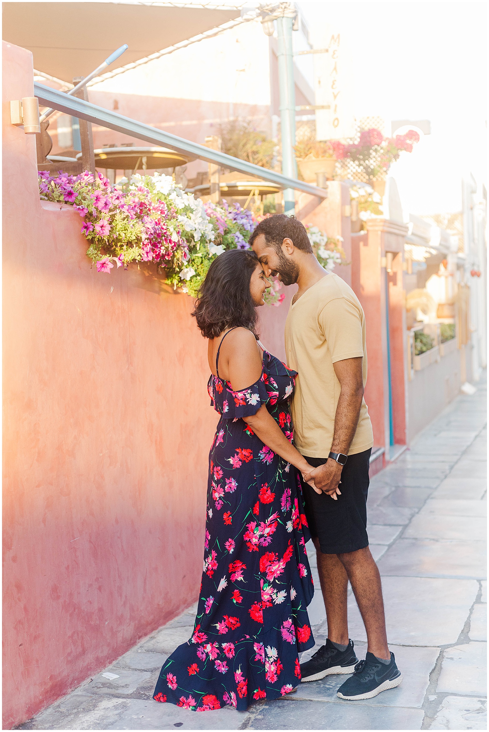 couple standing under flowers next to a pink wall greece photoshoot