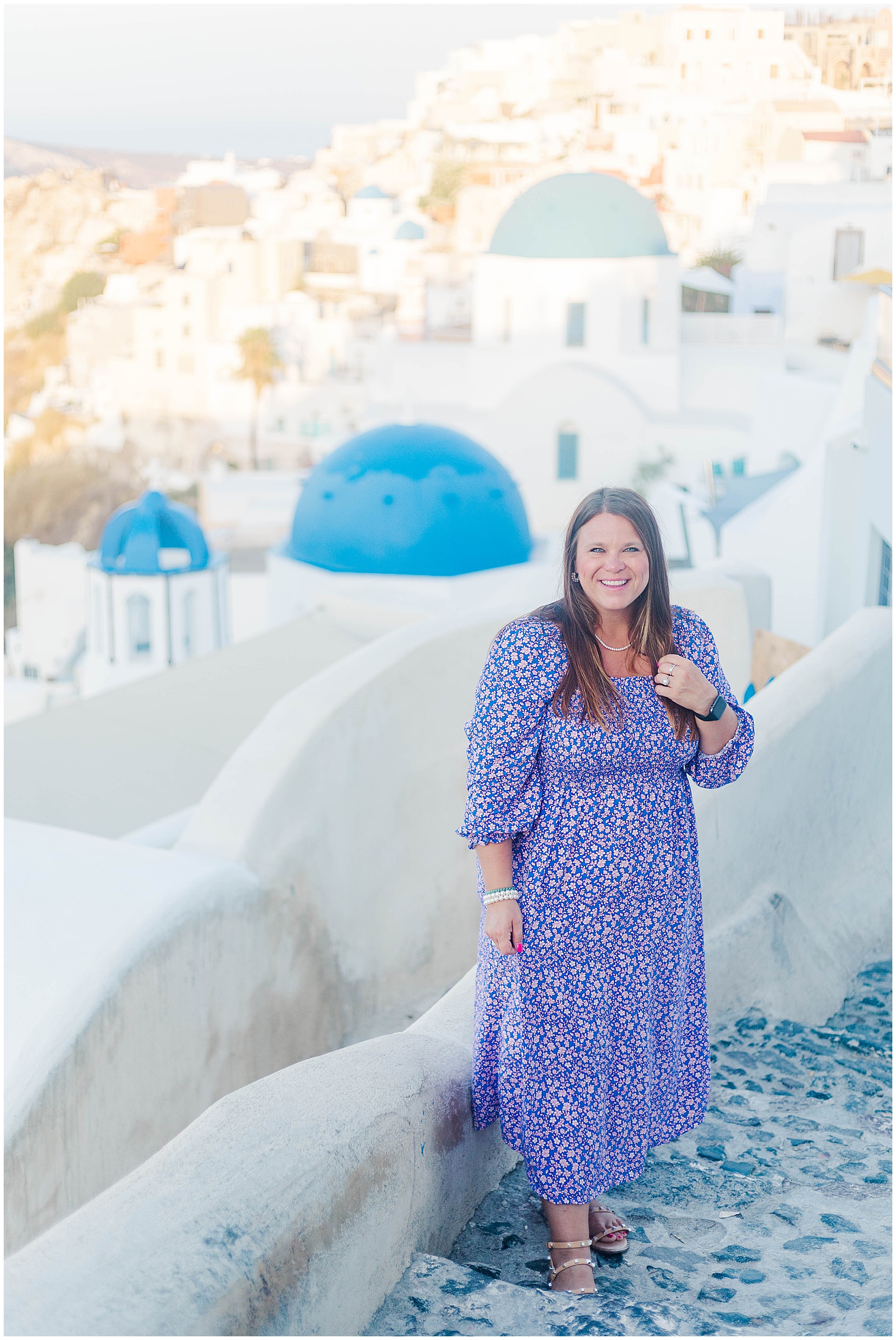 nicole standing above blue roofs in santorini greece photoshoot